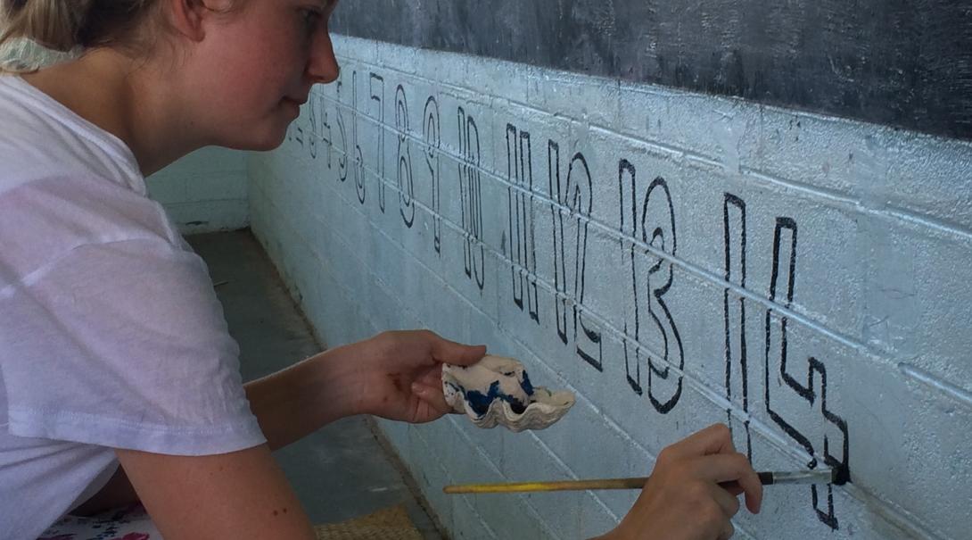 A Projects Abroad volunteer paints numbers in a classroom in Samoa A female volunteer working with children in Samoa for schoolies